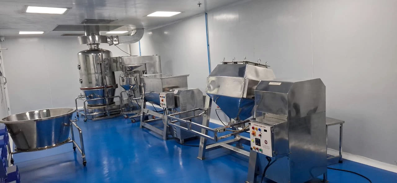 Original photograph of the Urmi Lifesciences production room with stainless-steel equipment and a blue floor